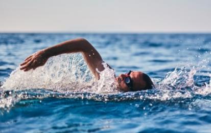 Persona che nuota nel mare con occhialini, sotto un cielo sereno.