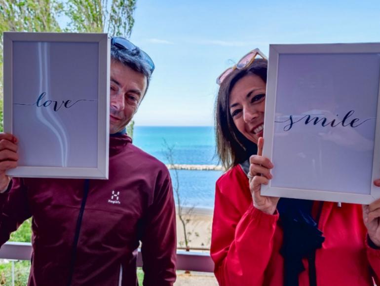 Due persone sorridono con cornici 'love' e 'smile' davanti al mare.